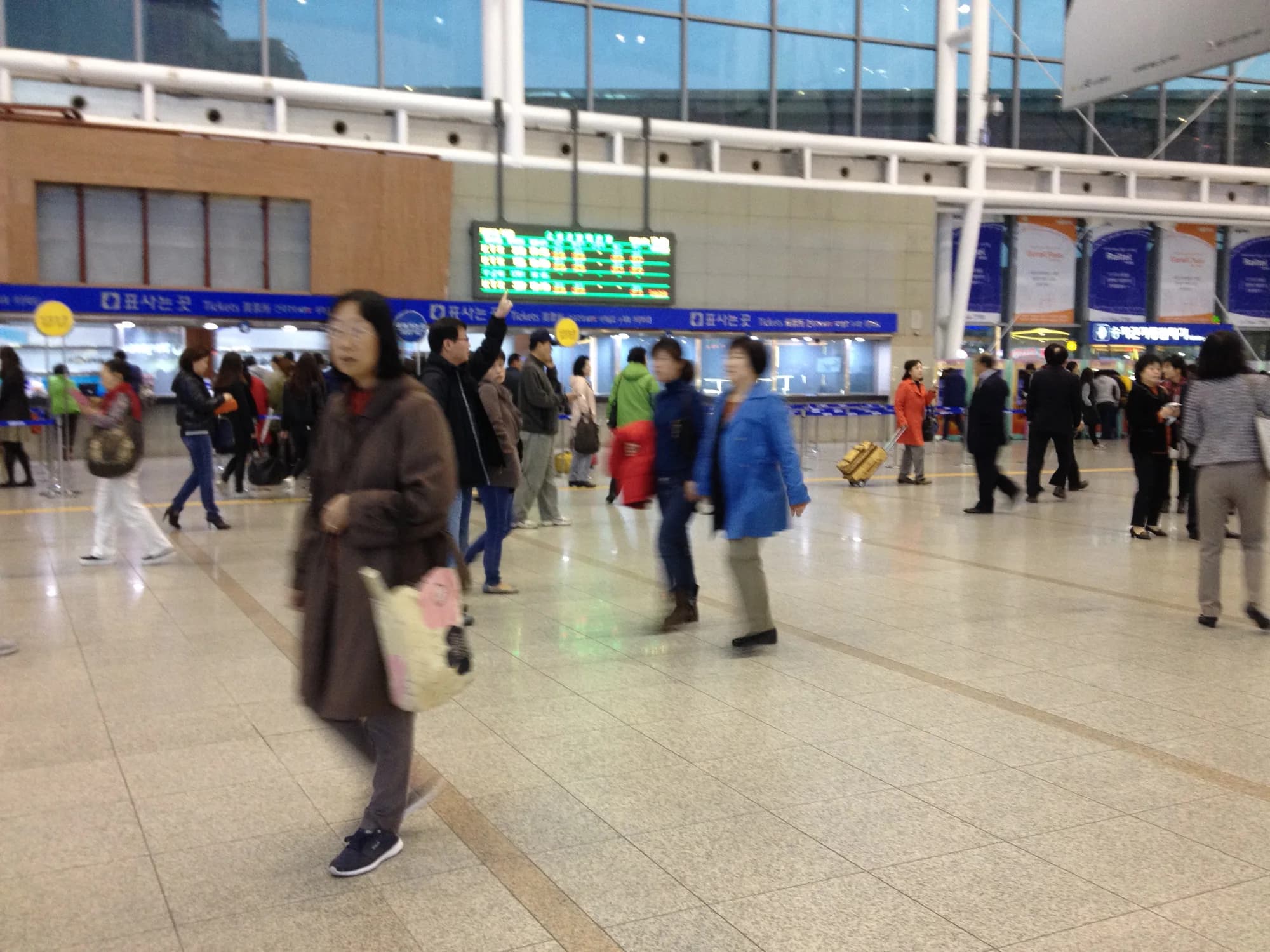 The interior concourse of Seoul Station with passengers and signs