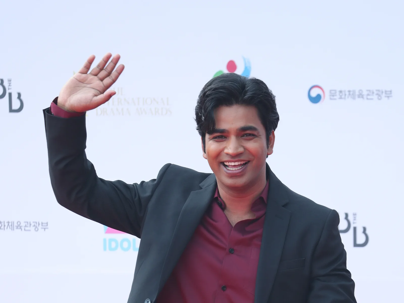 Anupam Tripathi smiles and waves on the red carpet at the 2022 Seoul International Drama Awards.