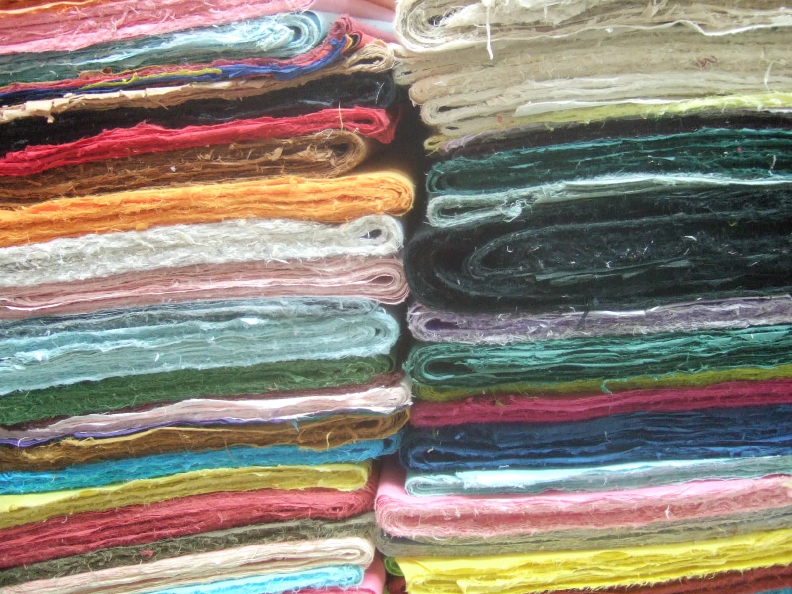 Stacks of folded, brightly colored handmade paper with visible fibers in Insadong, Seoul