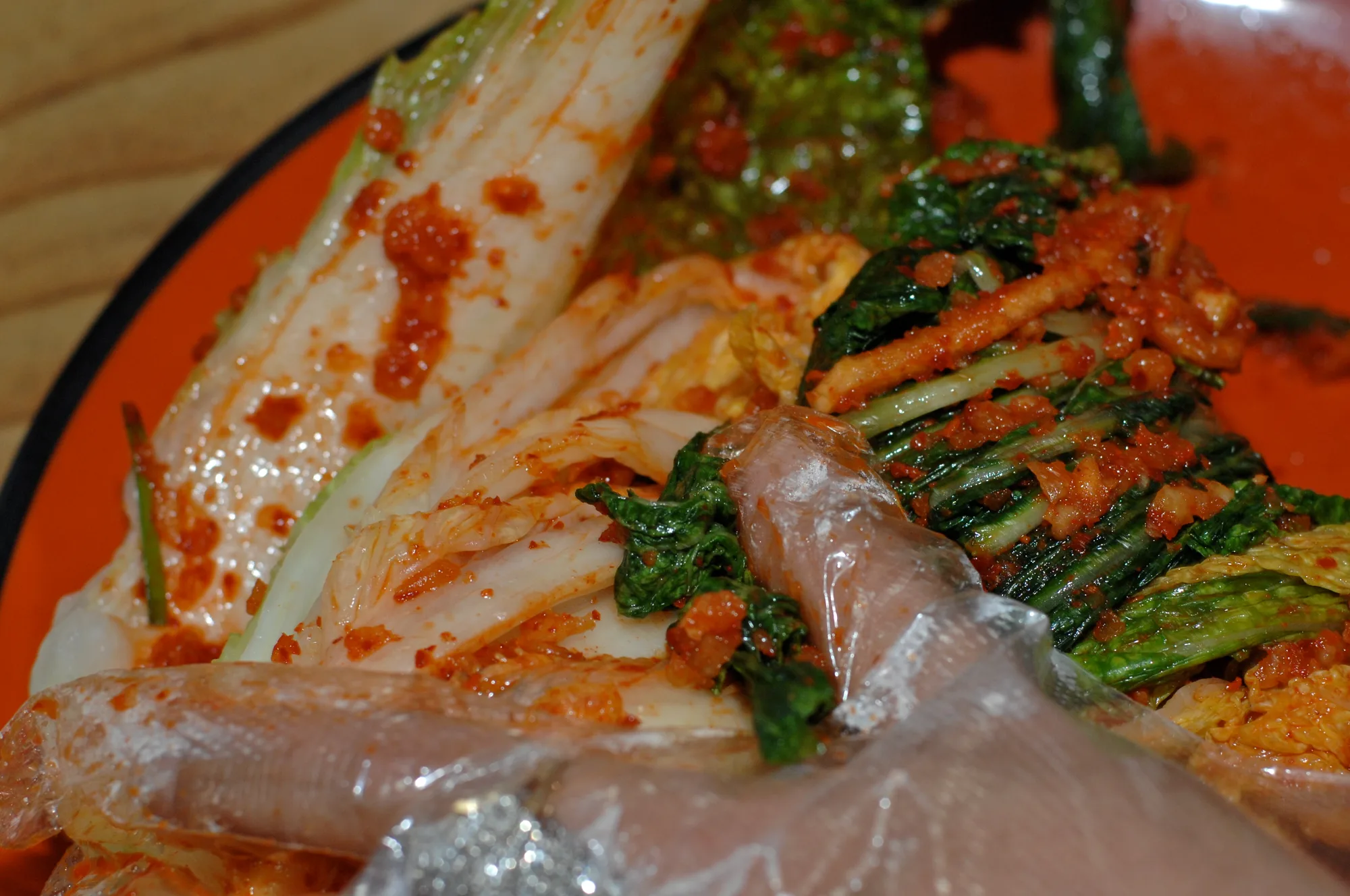 People seasoning napa cabbage together while making kimchi