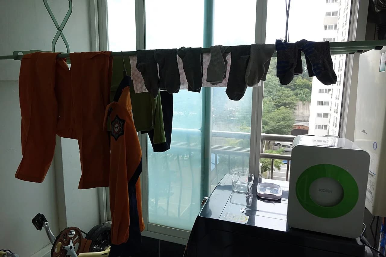 Laundry drying beside appliances on an enclosed Korean apartment balcony