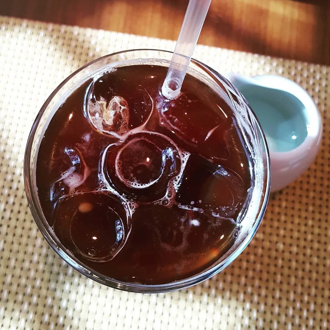 A clear cup of iced Americano beside a café window