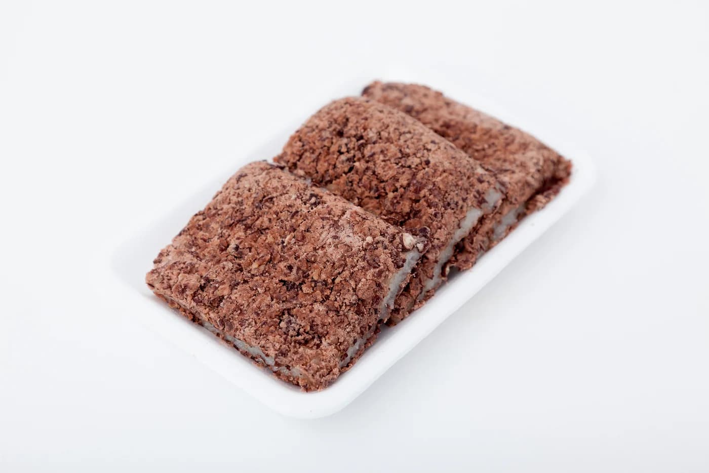 Rectangular pieces of brown-topped steamed rice cake arranged on a white tray.