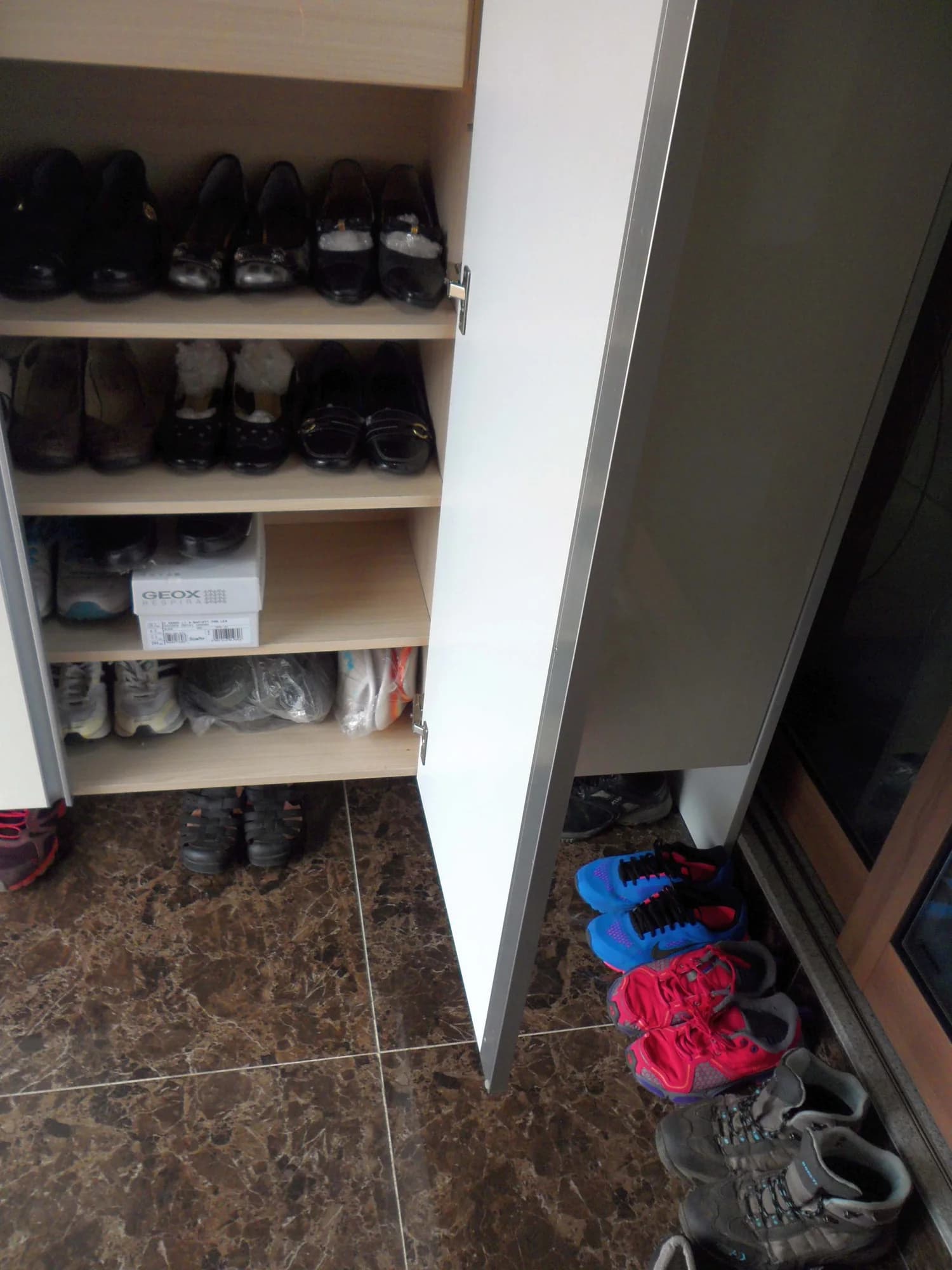 A tiled Korean home entrance with shoes and a wooden shoe rack