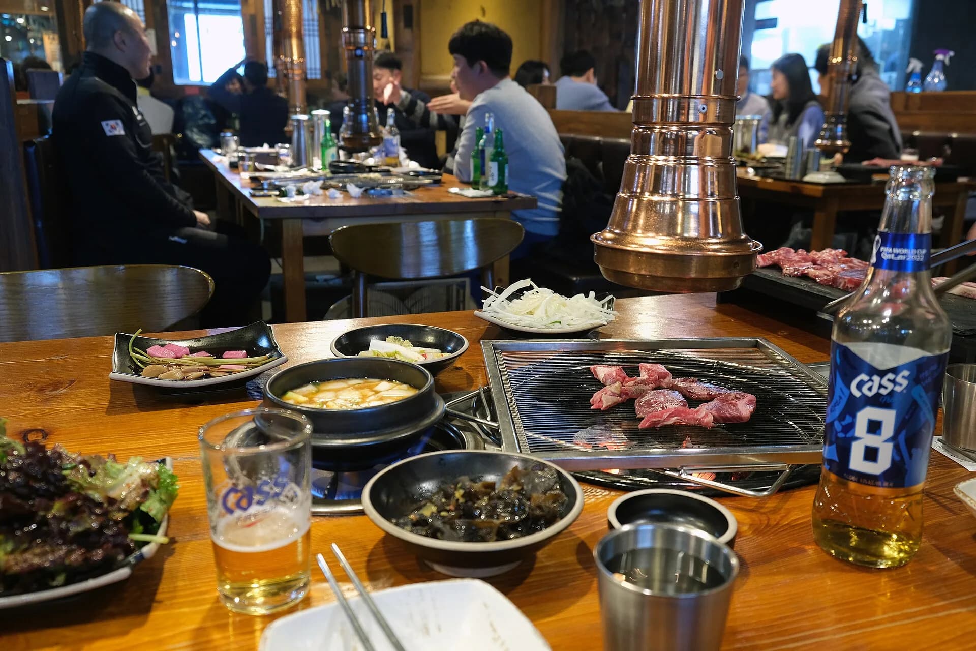 A Korean barbecue table in Seoul with meat cooking on the central grill